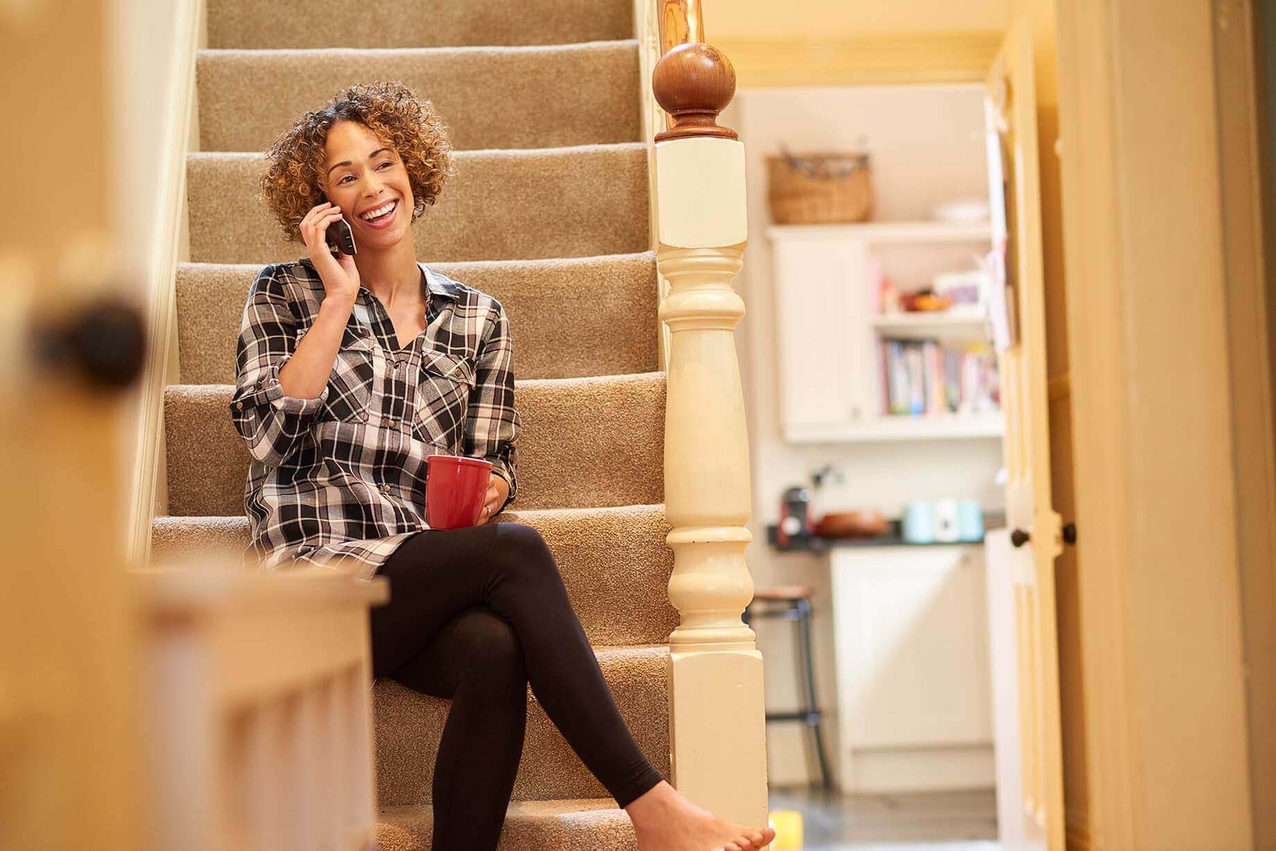 woman sitting on her stairs while speaking on her frontier landline