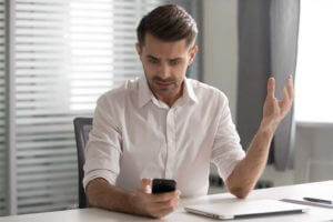 man using a cell phone while sitting at his desk