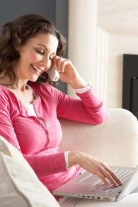 woman dressed in pink using her laptop while speaking on her frontier landline